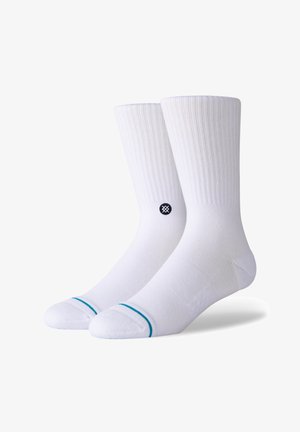 White cushioned socks with ribbed texture, featuring a contrasting turquoise stripe at the top and a circular black logo on the side.