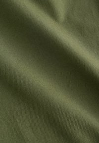 Nærbillede af glat, foldet olivengrønt stof med en fin diagonalt ribbet tekstur.