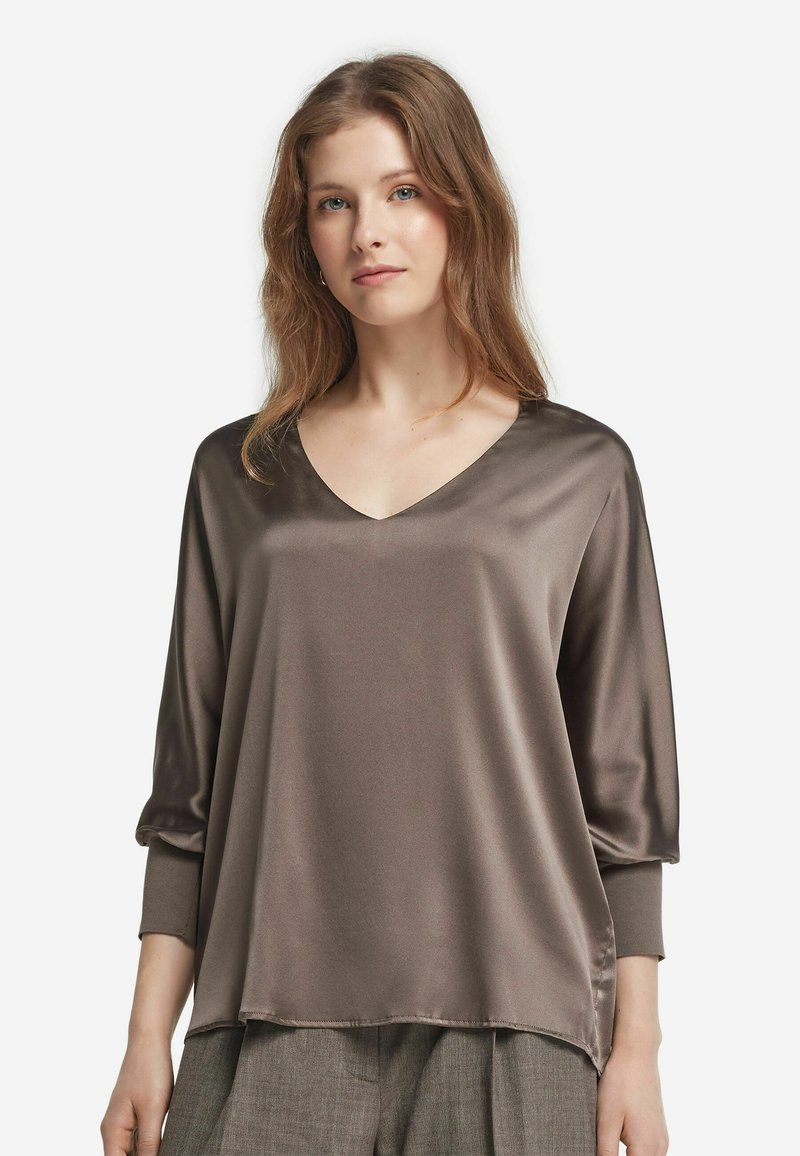 Blusa in satin marrone con scollatura a V, maniche a tre quarti e vestibilità rilassata. Texture liscia con un drappeggio fluido.