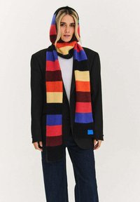 Wielokolorowy szalik w paski z mieszanki wełny, z żywymi czerwonymi, żółtymi, niebieskimi i czarnymi paskami; noszony jako kaptur i szalik.