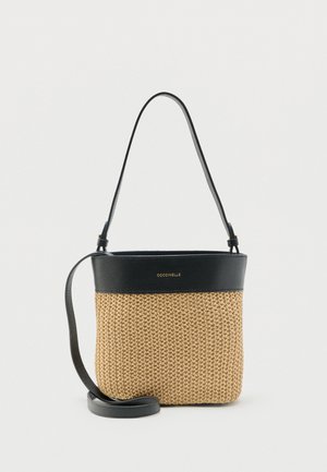 Lille bucket-taske med beige vævet krop, sort lædertop og stropper samt gyldent "COCCINELLE"-logo foran.