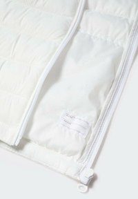 White quilted fabric with a smooth texture, featuring a zipper closure and a label with spaces for name and phone number.