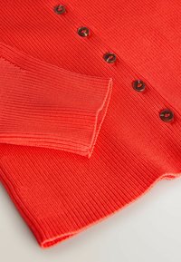 Cardigan roșu cu dungi, mâneci lungi, nasturi negri și textură netedă. Materialul are o ușoară elasticitate, îmbunătățind designul său mulat.