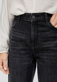 Jeans in denim nero a vita alta, con leggera scoloritura, design a cinque tasche e chiusura frontale con bottone in metallo.