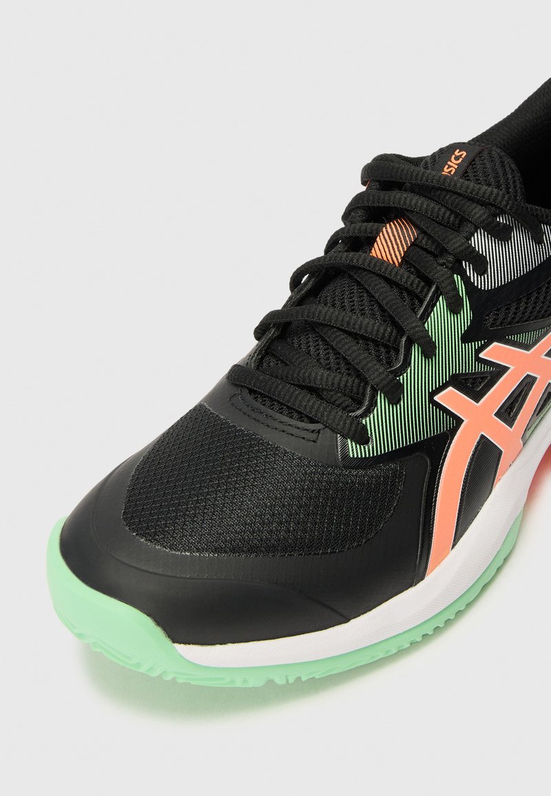 Scarpa sportiva nera con una tomaia in rete, suola verde e bianca e dettagli arancioni. Presenta materiali testurizzati e un design della punta curvo.