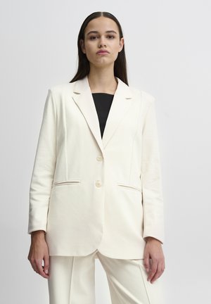 Slonovinový blazer vyrobený z měkké látky, s klopovým límcem, dvěma knoflíky a bočními kapsami. Design je přizpůsoben s uvolněným střihem.
