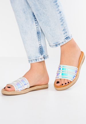 Klapy z holograficznym paskiem, kremowymi paskami i plecionymi, jutowymi podeszwami. Posiadają otwarty nos i płaską podeszwę.