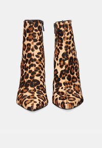 Par de botines de tacón alto con estampado de leopardo marrón y negro y cremalleras laterales, exhibidos sobre un fondo blanco.