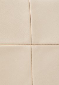 Ljusbeige läderklädsel med en slät textur, med horisontella och vertikala sömmar som skapar ett rutmönster.