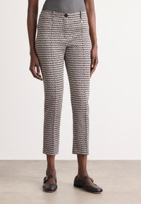 Schmal zulaufende Hosen in einem schwarz-weißen abstrakten Muster, mit Knopf- und Reißverschluss, seitlichen Taschen und einer mittelhohen Taille.