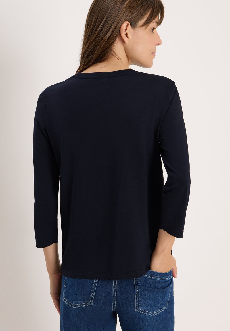 T-shirt bleu marine à manches longues avec un col rond. Matériau doux avec une texture lisse et une coupe décontractée. La vue arrière montre des détails de couture.