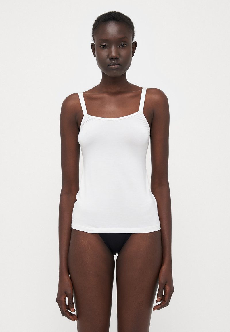 Witte top met dunne bandjes, aansluitend ontwerp, gemaakt van zachte stof. Draagt met bijpassende zwarte onderkleding.