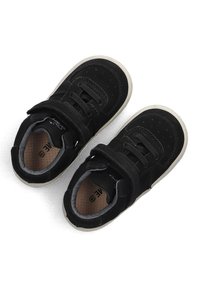 Zwarte suède sneakers met een gewatteerde kraag, vetersluiting en klittenband. Rubberen zool met beige accenten en geperforeerde details op de teen.