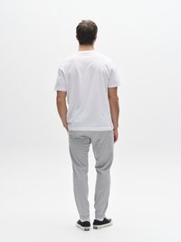 White short-sleeve t-shirt, light grey sweatpants with elastic cuffs, and black sneakers. Simple design, casual fit, solid colors.