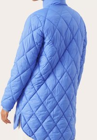 Jasnoniebieska pikowana kurtka z wysokim kołnierzem, w rombowy wzór, z bocznymi rozcięciami, wykonana z gładkiego, błyszczącego materiału.