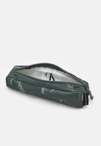 Felpa verde con chiusura a zip, caratterizzata da una texture liscia e un motivo astratto. Include un'etichetta all'interno. Forma compatta e rettangolare.