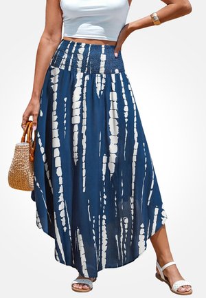 Marineblaue Maxirock aus leichtem Stoff mit weißen abstrakten Mustern, gerafftem Bund und fließendem Saum. Kombiniert mit einer gewebten Tasche und Sandalen.