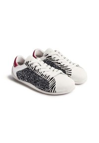 Zapatillas blancas con un panel de purpurina negra brillante y un diseño de rayas de cebra en los lados. Con un refuerzo en la parte trasera de color burdeos.