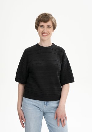 Schwarzer Strickpullover mit strukturiertem Streifenmuster, kurzen Ärmeln und rundem Halsausschnitt, kombiniert mit hellblauen Jeans.