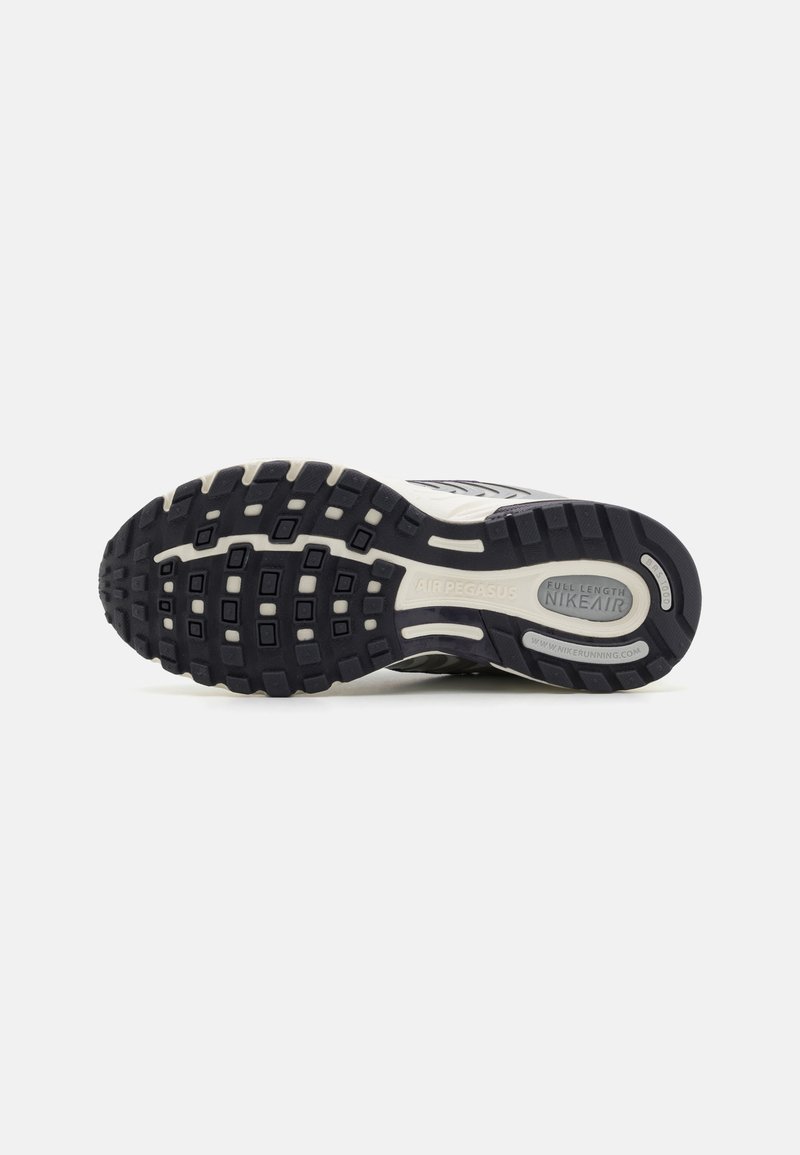 La suela de la zapatilla de correr Nike Air Pegasus presenta goma negra texturizada con un patrón de banda de rodadura multidireccional y detalles de marca visibles.