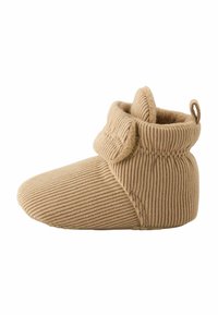 Chausson en velours côtelé beige avec un design à revers, texture douce, bout arrondi et une petite boucle pour un enfilage facile. La surface présente un motif à côtes.