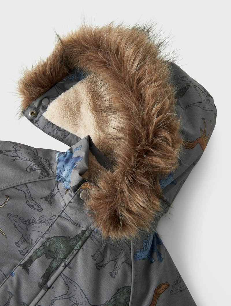 Grijze buitenjas met een met bont gevoerde capuchon, versierd met kleurrijke dinosaurusthema's. Het materiaal lijkt zacht, met een pluizige binnenvoering.