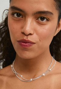 Collier multi-brins composé de chaînes en argent, d'accents texturés et de perles décoratives. Design simple et élégant, adapté à différentes tenues.
