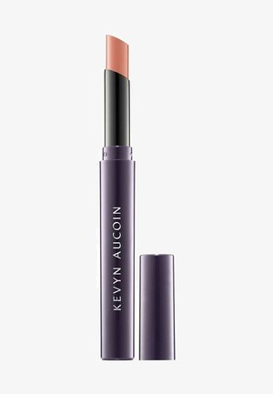 Kevyn Aucoin lip product with a purple cylindrical case, featuring a curved nude lip color stick. The cap is removable for use.
