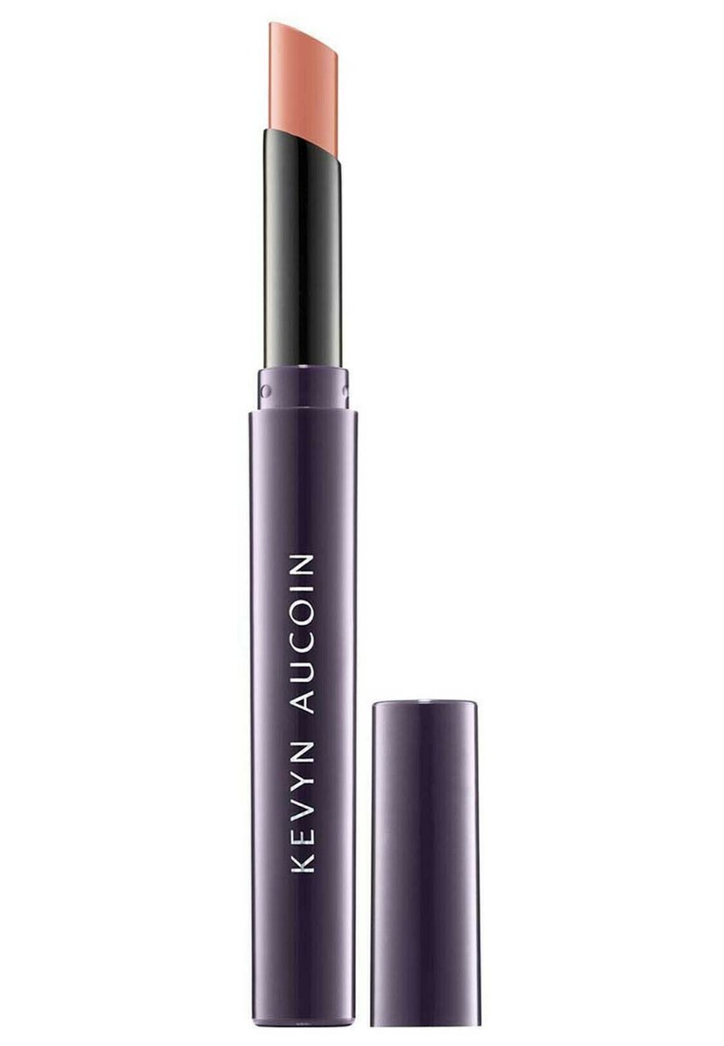 Kevyn Aucoin Lippenprodukt in einem lila zylindrischen Gehäuse, das einen gebogenen nude-farbenen Lippenstift enthält. Der Deckel ist abnehmbar zur Verwendung.