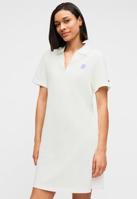 Φόρεμα πόλο ανοιχτό πράσινο με κοντά μανίκια, λαιμόκοψη σε σχήμα V και διακριτική κεντημένη λογότυπο στο στήθος. Μαλακό, υφασμάτινο με υφή.
