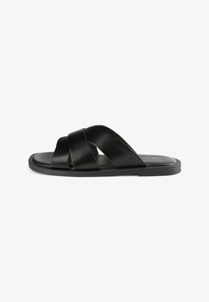 Black slide sandals with crossed straps made of textured synthetic material, featuring a smooth footbed and a grooved rubber sole.