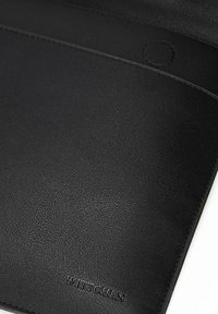 Zwarte leren documentfolio met een subtiele textuur, gestikte accenten en een cirkelvormig detail. Merknnaam "WITTCHEN" is in het oppervlak geperst.