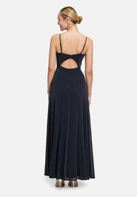 Abito maxi in blu navy con corpo aderente, spalline sottili e schiena scoperta. Presenta una gonna fluente realizzata in tessuto scintillante.