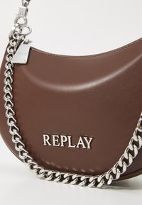 Borsa in finta pelle marrone con una forma curva, tracolla in catena argentata e dettagli del logo metallici. Texture liscia e design minimalista.