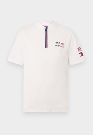 White polo shirt with a collar, zip closure, and short sleeves. Features "USA" and "SAIL GP TEAM" embroidered in black, with flag accents.