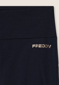 Leggings blu navy realizzati in tessuto morbido, con un ampio elastico in vita. Presentano il logo dorato "FREDDY" e una striscia laterale a contrasto con il branding.