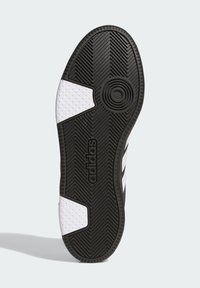 Czarna gumowa podeszwa trampka z białymi akcentami, z wzorem w jodełkę, okrągłymi detalami bieżnika oraz wytłoczonym logo po boku.