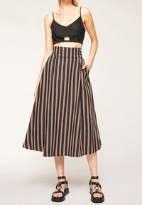 Svart och rosa randig midikjol med hög midja och sidoficka, kombinerad med en svart kortärmad tanktop och svarta sandaler med remmar.