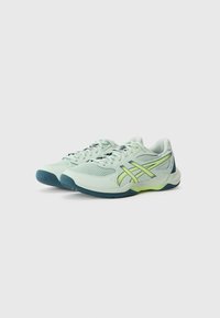 Baskets de sport vert clair avec tige en mesh, accents jaunes et semelles en caoutchouc bleues. Présentent un bout arrondi et un design à lacets.