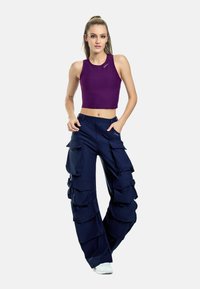 Lila kortärmad tanktopp och marinblå cargobyxor med flera fickor, med lös passform och mjukt tyg. Vita sneakers fulländar looken.