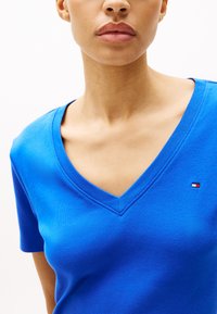 Blauwe katoenen T-shirt met korte mouwen, met een V-hals ontwerp en een klein geborduurd logo op de linkerborst. Soepele textuur, aansluitende pasvorm.
