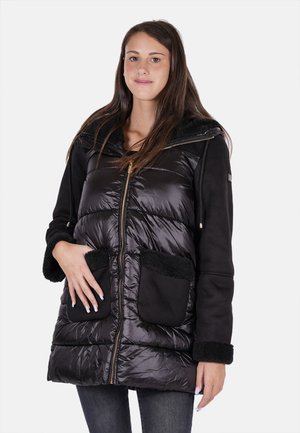 Giacca a vento nera con grandi tasche frontali, chiusura con zip e colletto foderato in morbido pile. Presenta una texture esterna lucida.