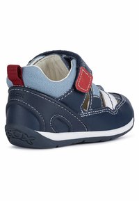 Sandalia infantil de color azul marino hecha de cuero y tela con cierre de Velcro, acentos blancos y un diseño de corte lateral con patrón.