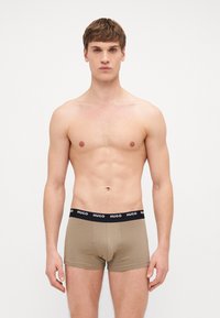 Schwarze Boxershorts aus glattem Stoff mit einem braunen "HUGO" Logo-Bund, tailliertem Schnitt und mittellanger Länge bis zum Oberschenkel.