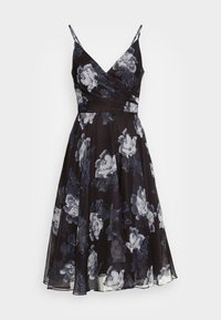 Vestido floral preto com decote em V, alças finas e corpete justo. Apresenta uma saia esvoaçante com textura translúcida e padrões florais brancos.