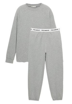 Maglia grigia a maniche lunghe e pantaloni da jogging abbinati. Materiale in misto cotone, polsini a coste, logo del marchio ricamato in vita. Texture morbida.