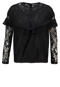 Haut en dentelle noire avec des manches longues ornées de détails en dentelle, des accents volants le long de l'encolure et une fermeture éclair au dos.