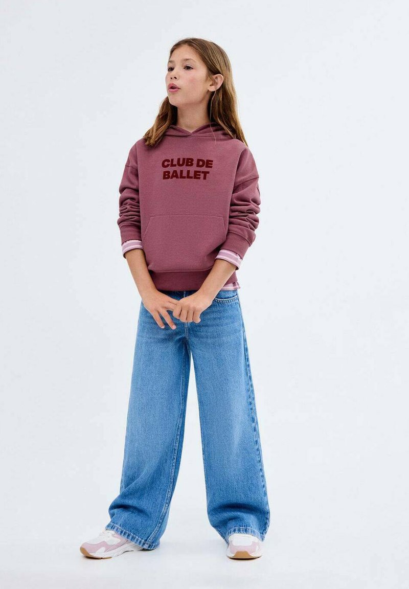 Burgundská mikina s kapucí s potiskem "CLUB DE BALLET" v hnědé barvě, v kombinaci s světle modrými širokými džíny a bílými teniskami s růžovými detaily.