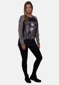 Long-sleeve, navy sweatshirt with gray sleeves, featuring a white graphic of characters from "The Nightmare Before Christmas" and text accent.