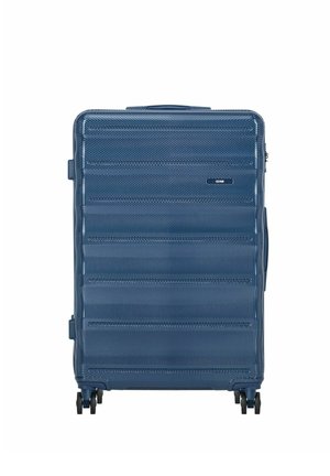 Niebieska walizka z twardą obudową z teksturowanymi poziomymi rowkami, cztery podwójne obrotowe kółka i uchwyt do przenoszenia na białym tle.